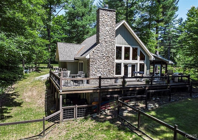 back of property with a shingled roof, a chimney, and a wooden deck