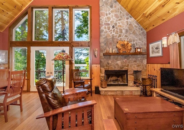 interior space featuring high vaulted ceiling, wooden ceiling, a stone fireplace, and light wood finished floors