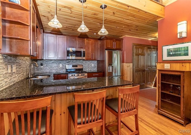 kitchen featuring open shelves, stainless steel appliances, light wood-style flooring, a sink, and a peninsula