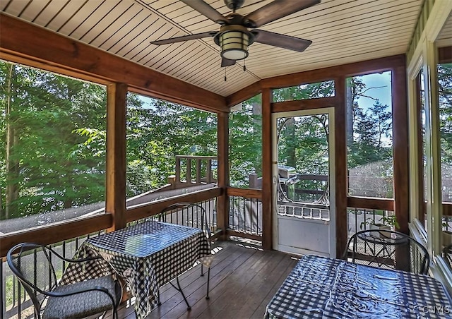 unfurnished sunroom featuring vaulted ceiling, wooden ceiling, and a ceiling fan