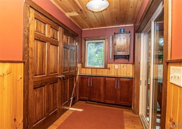 interior space featuring wooden ceiling, light wood-style flooring, a wainscoted wall, and wood walls