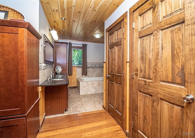 bathroom with a bath, wood finished floors, vanity, and wood ceiling