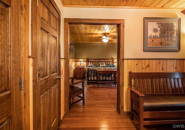 interior space featuring a wainscoted wall, wood finished floors, wood ceiling, and wooden walls