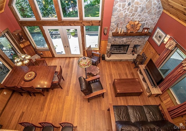 living area featuring a fireplace, a high ceiling, wood finished floors, and french doors