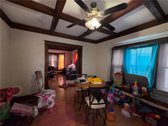 dining area featuring beam ceiling, coffered ceiling, ceiling fan, and wood finished floors