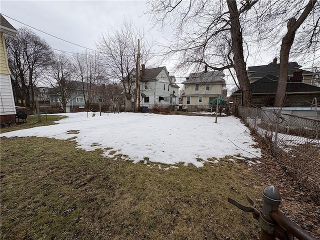 yard layered in snow featuring a residential view and fence