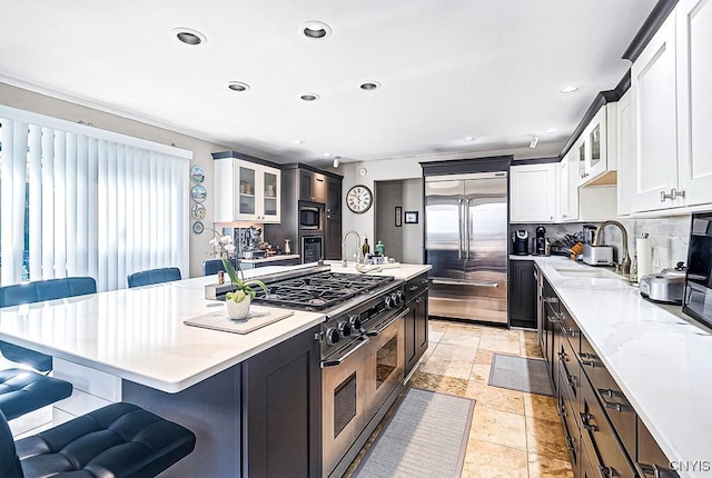 kitchen featuring built in appliances, a sink, a kitchen breakfast bar, decorative backsplash, and glass insert cabinets