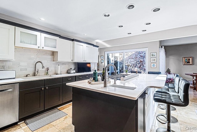 kitchen featuring dishwasher, light countertops, a breakfast bar, and a sink