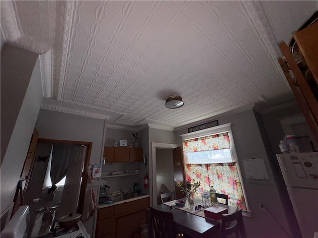 kitchen featuring an ornate ceiling, ornamental molding, a sink, and refrigerator