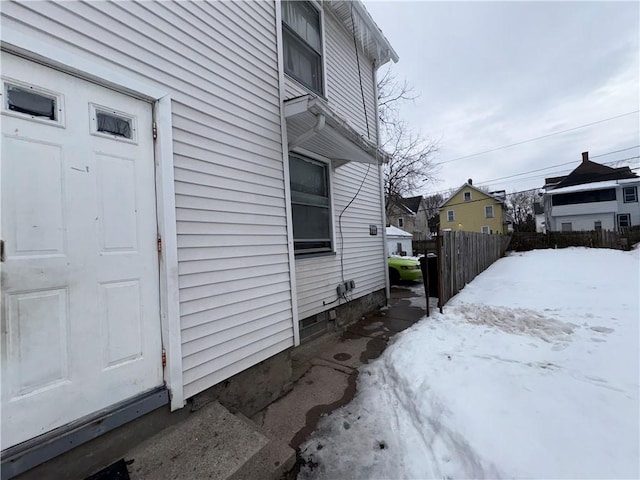 snow covered property featuring a residential view and fence