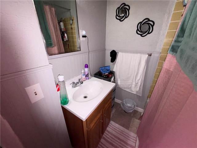 full bath featuring curtained shower, wainscoting, vanity, and tile patterned floors