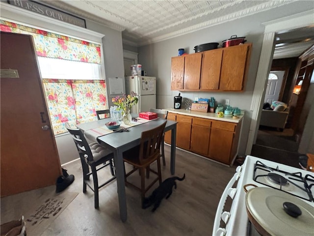 kitchen featuring white appliances, brown cabinetry, an ornate ceiling, dark wood-style flooring, and light countertops