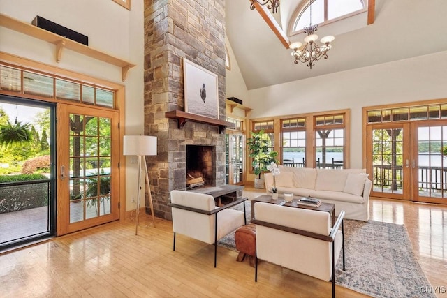 living area with a stone fireplace, french doors, plenty of natural light, and an inviting chandelier