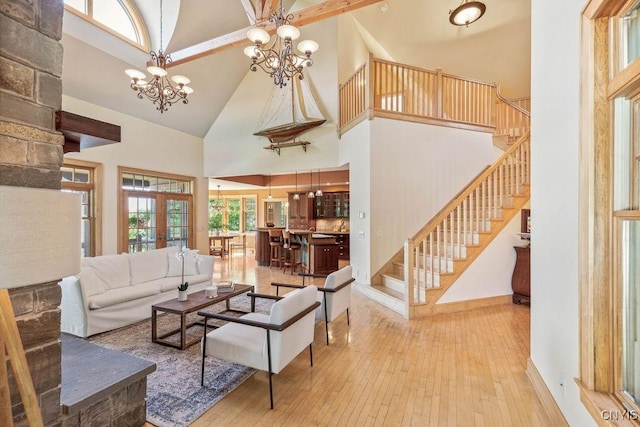 living area featuring a towering ceiling, wood-type flooring, stairway, an inviting chandelier, and french doors