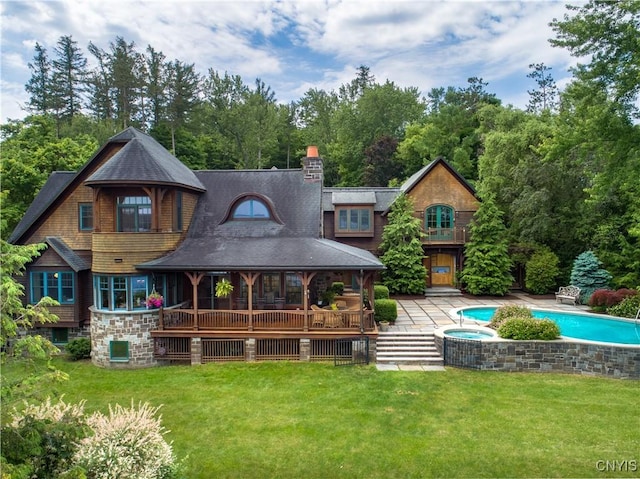 back of property with a chimney, an outdoor pool, a patio, and a yard