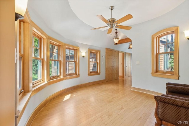 living area featuring baseboards, vaulted ceiling, a ceiling fan, and light wood-style floors