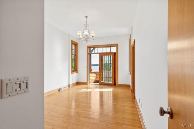 foyer featuring a notable chandelier, light wood finished floors, visible vents, and baseboards