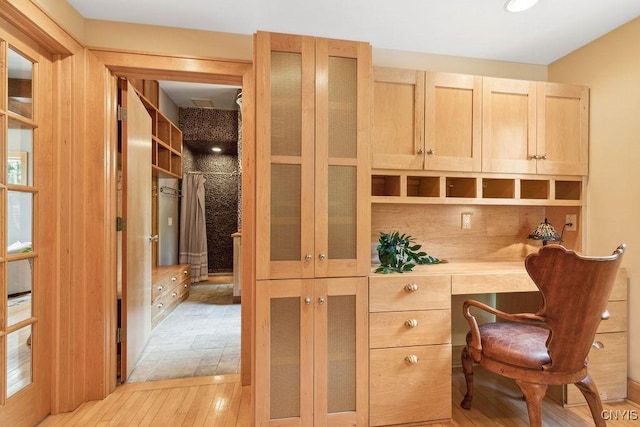 office area with light wood-style flooring and built in study area