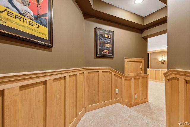 hallway featuring a wainscoted wall and carpet flooring