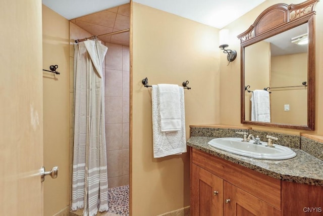 bathroom with tiled shower and vanity