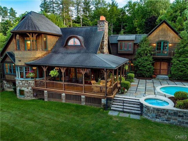 rear view of house featuring a yard, a patio area, a balcony, an in ground hot tub, and an outdoor pool