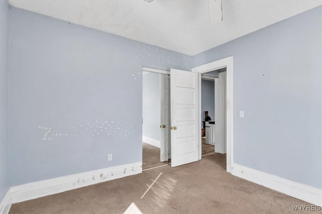 unfurnished bedroom with ceiling fan, a closet, carpet flooring, and baseboards