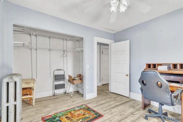 office space featuring radiator heating unit, wood finished floors, a ceiling fan, and baseboards