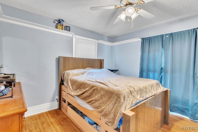 bedroom with a textured ceiling, light wood-type flooring, a ceiling fan, and baseboards