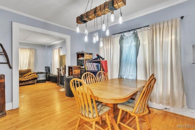 dining area with ornamental molding and light wood-style floors