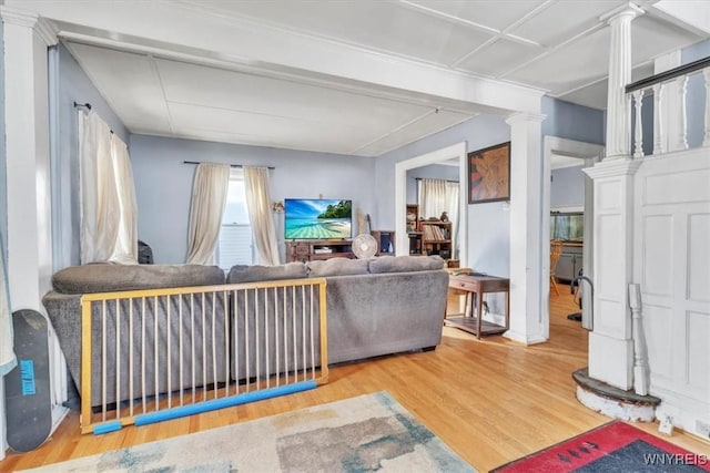 living area with decorative columns and wood finished floors