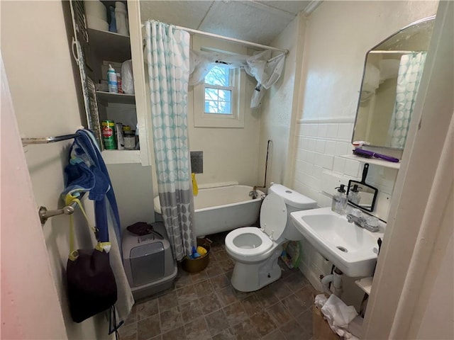 bathroom featuring shower / tub combo with curtain, tile walls, toilet, wainscoting, and a sink