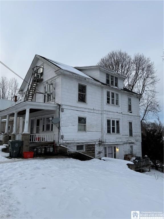 snow covered property with covered porch