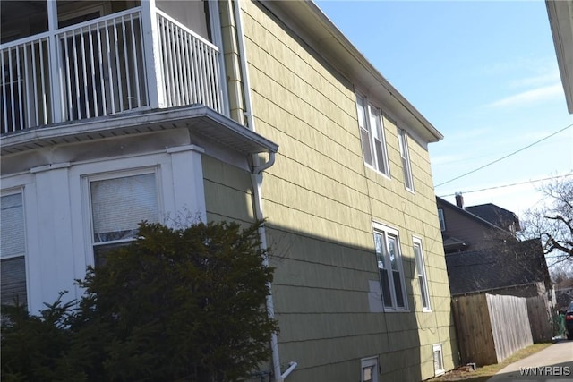 view of side of home with fence and a balcony