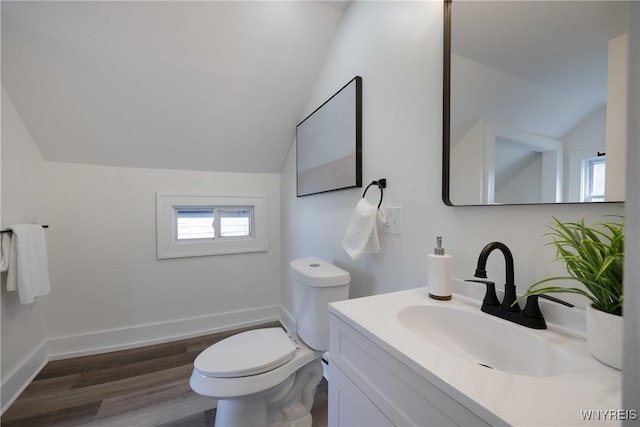 half bathroom with baseboards, toilet, wood finished floors, vaulted ceiling, and vanity