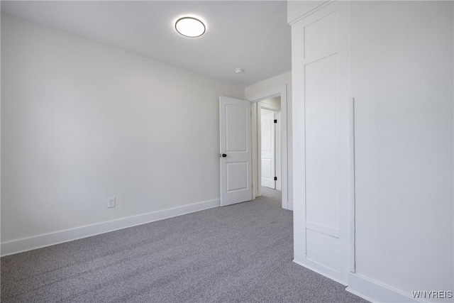 carpeted spare room featuring baseboards