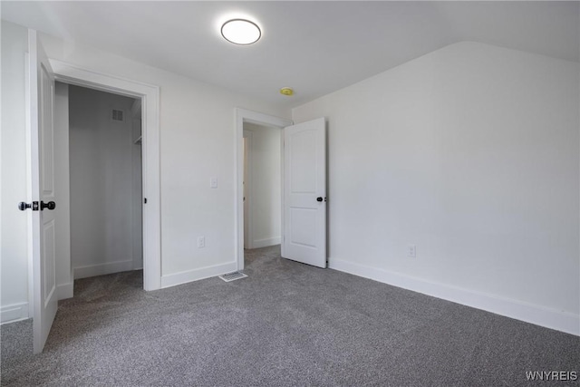 unfurnished bedroom with carpet, visible vents, vaulted ceiling, and baseboards