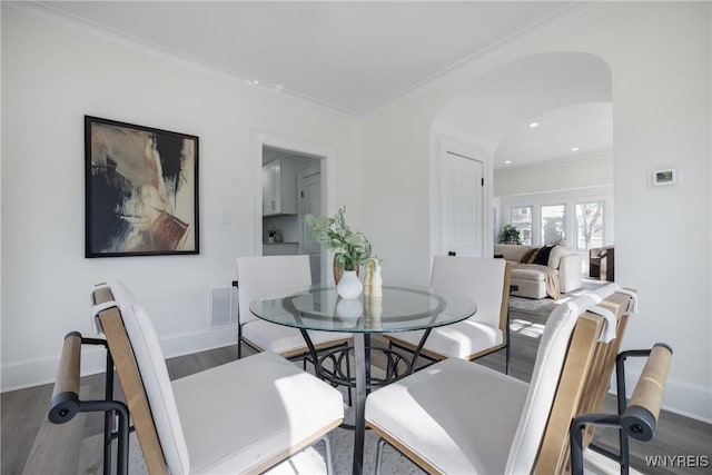 dining space featuring crown molding, arched walkways, and wood finished floors