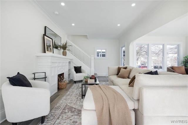 living area with baseboards, a high end fireplace, ornamental molding, wood finished floors, and recessed lighting