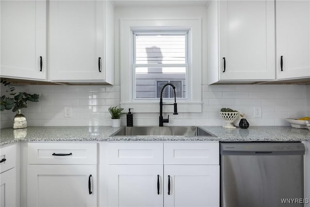 kitchen featuring tasteful backsplash, white cabinets, dishwasher, and a sink