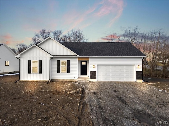 single story home with driveway, an attached garage, a shingled roof, and board and batten siding