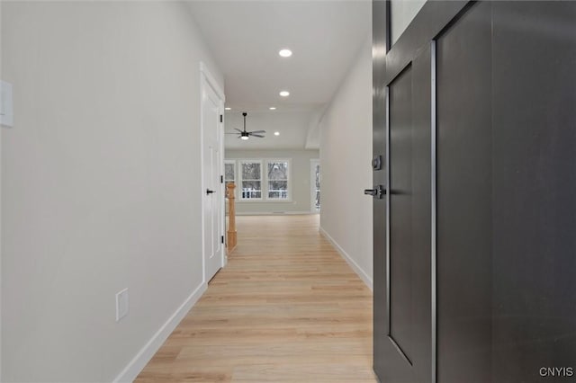 corridor with light wood-type flooring, baseboards, and recessed lighting