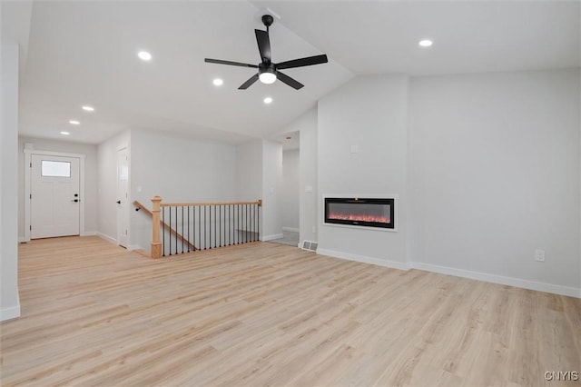 unfurnished living room featuring recessed lighting, a glass covered fireplace, vaulted ceiling, wood finished floors, and baseboards