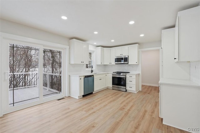 kitchen featuring light countertops, visible vents, light wood-style flooring, appliances with stainless steel finishes, and white cabinets