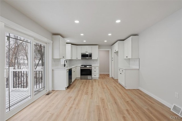 kitchen featuring stainless steel appliances, light countertops, visible vents, and backsplash