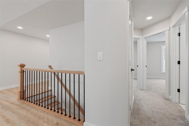 hall with carpet, baseboards, an upstairs landing, and recessed lighting