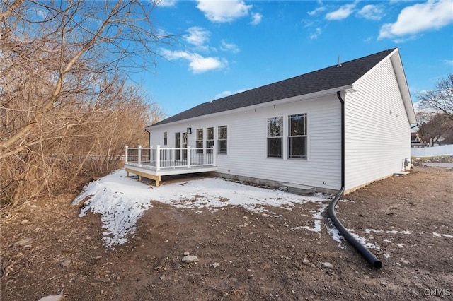 snow covered back of property featuring a deck