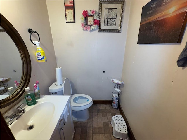 bathroom with toilet, baseboards, and vanity