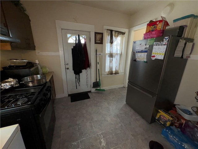 kitchen with black range with gas cooktop, baseboards, and freestanding refrigerator