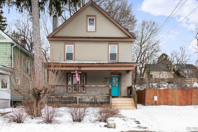 traditional style home with covered porch, a chimney, and fence