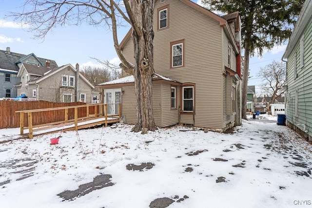 snow covered rear of property featuring a residential view and fence